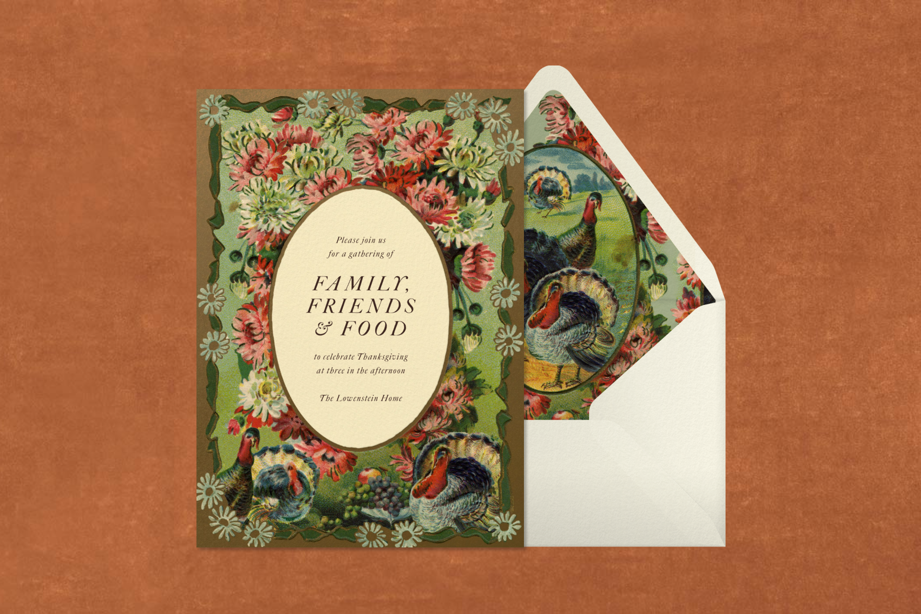 A vintage-style Thanksgiving invitation with a border of pink and white flowers and turkeys and text reading ‘Family, friends & food’ sits beside a cream envelope with a turkey-print liner against a textured rust backdrop.