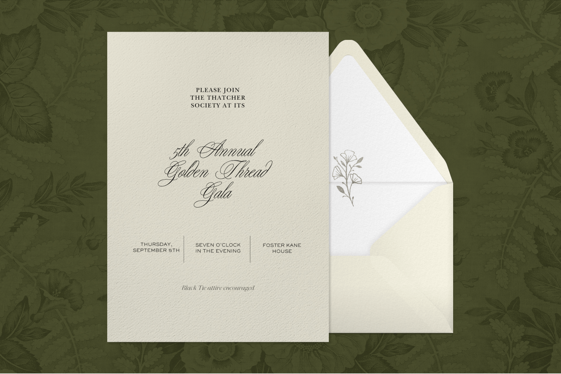 An ivory cardstock gala invitation sits to the left of an ivory envelope with a floral-motif interior against a forest-green floral backdrop.