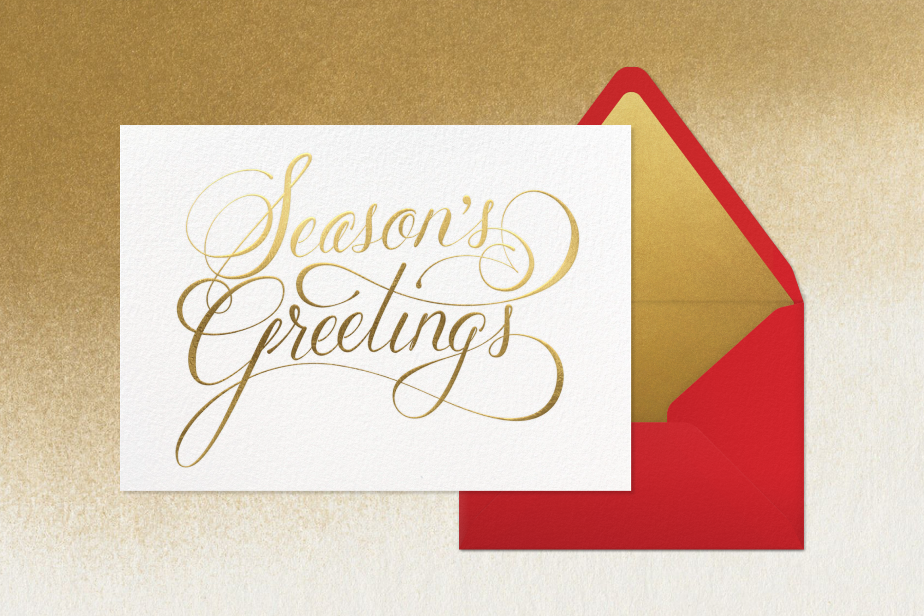 A holiday card with swirling gold foil script that reads ‘Season’s Greetings’ paired with a red envelope.