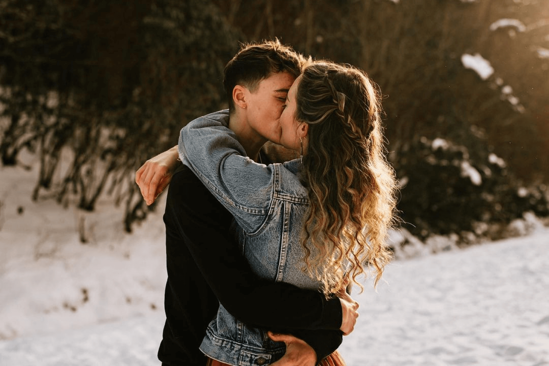 two people embrace and kiss in a snowy setting