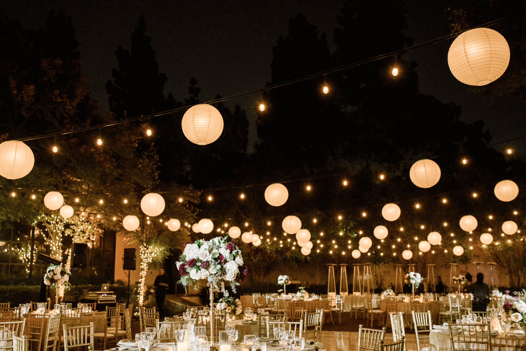 outdoor wedding reception setup at night with orb string lights