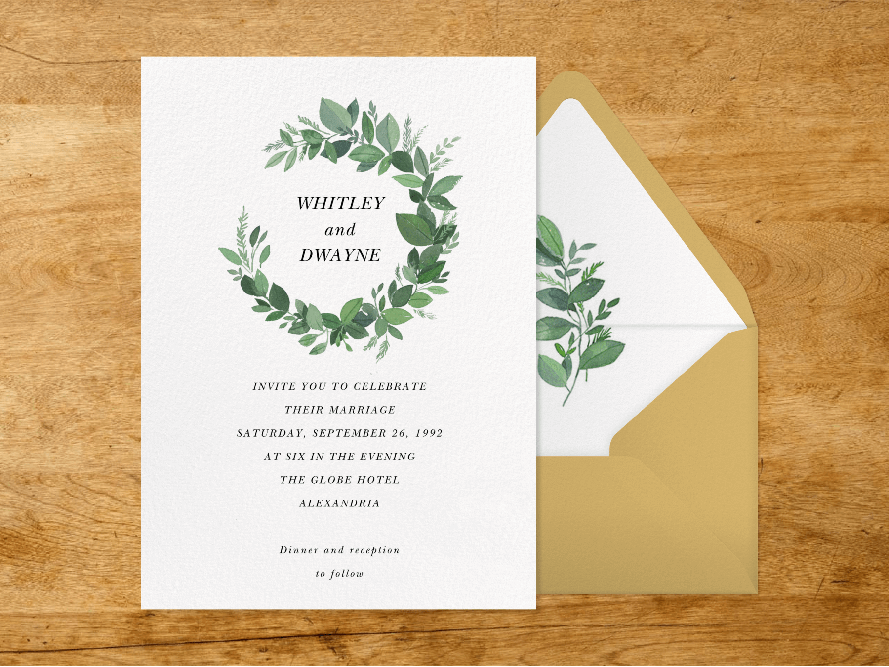 A wedding invitation with a green leaf wreath around the names.