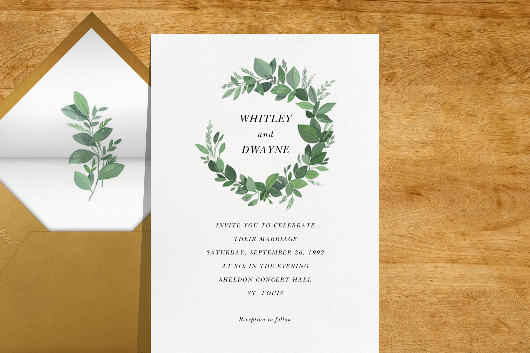 wedding invitation with a green leaf wreath around the names
