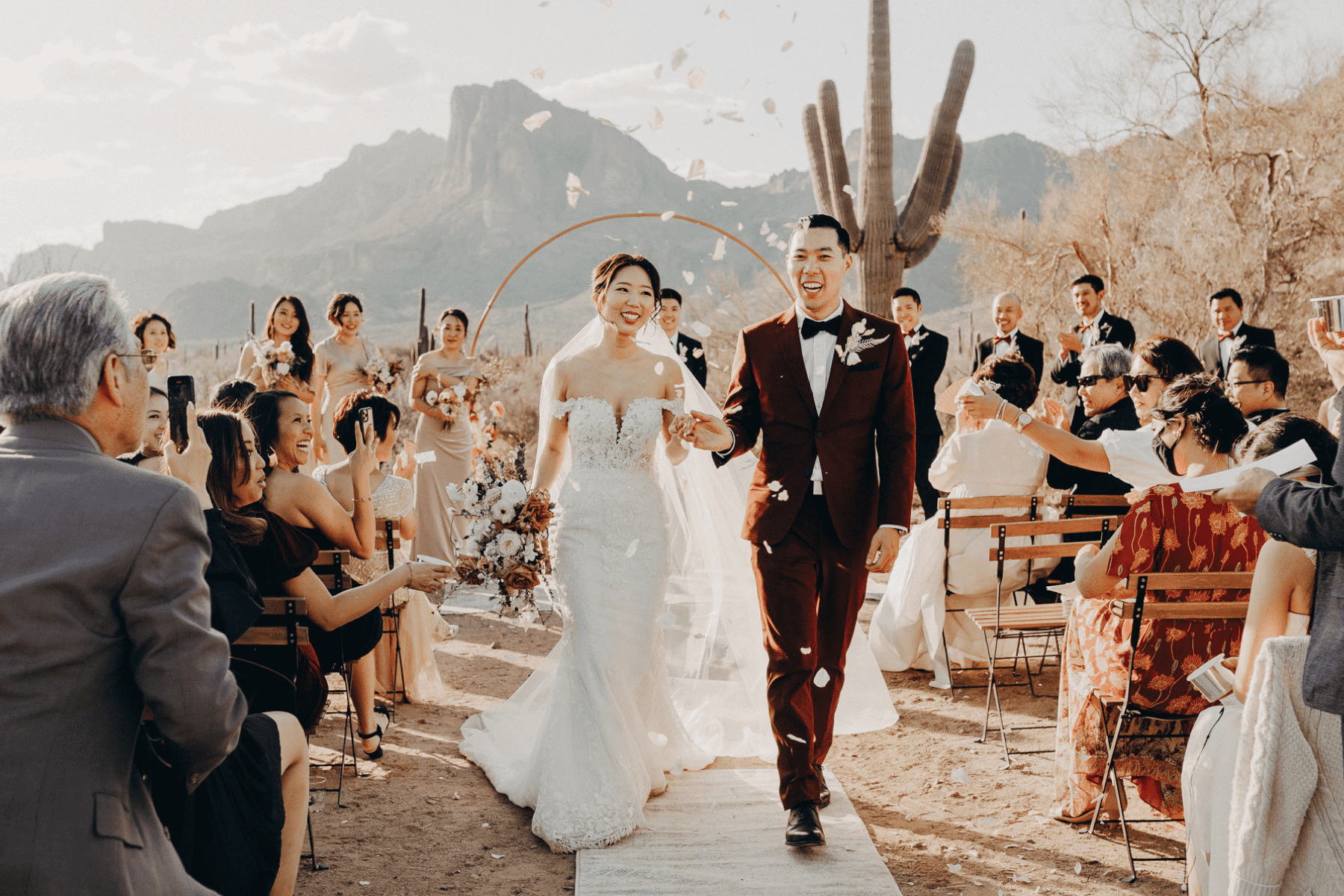 A newly married couple walks back down the aisle as guests throw flower petals.