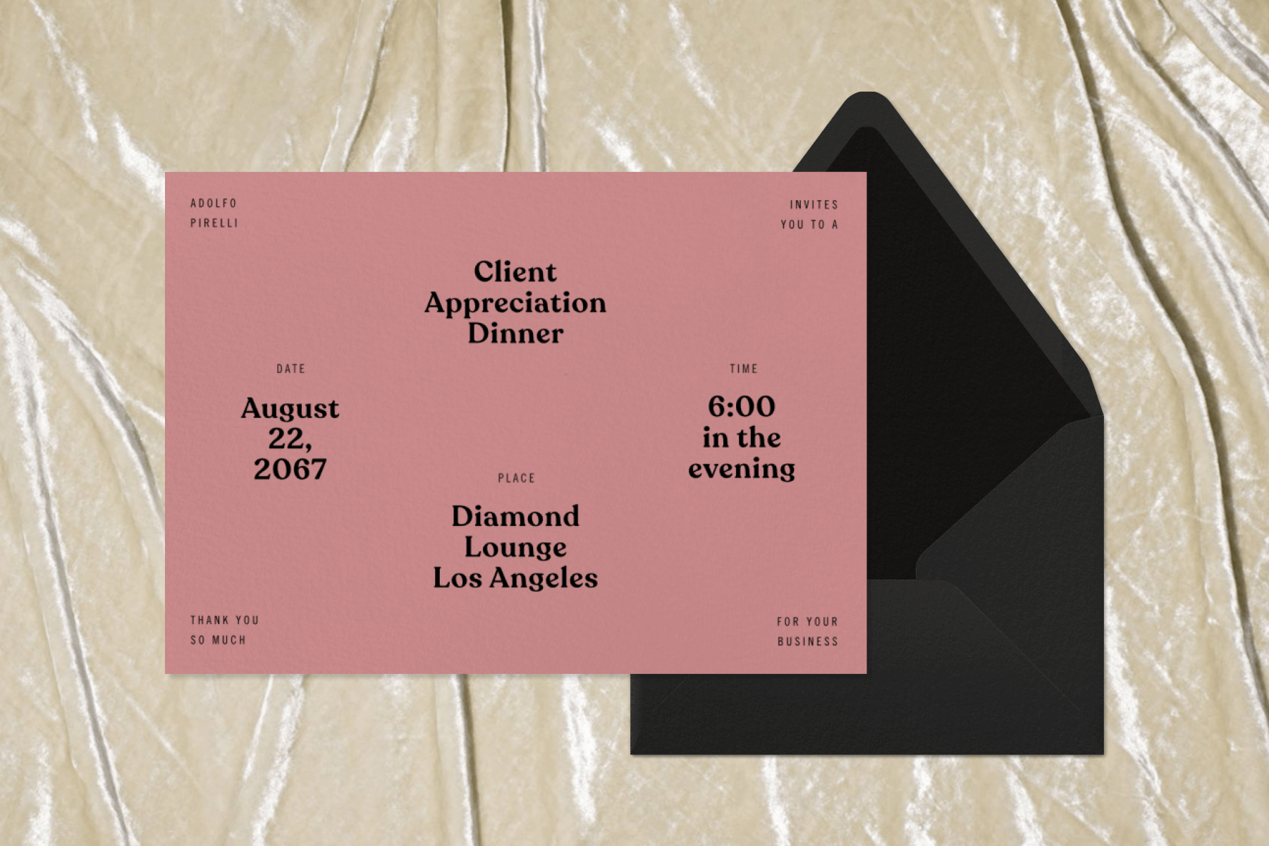 A dusty pink invitation to a client appreciation dinner set on a black envelope on top of a tan velvet backdrop. 