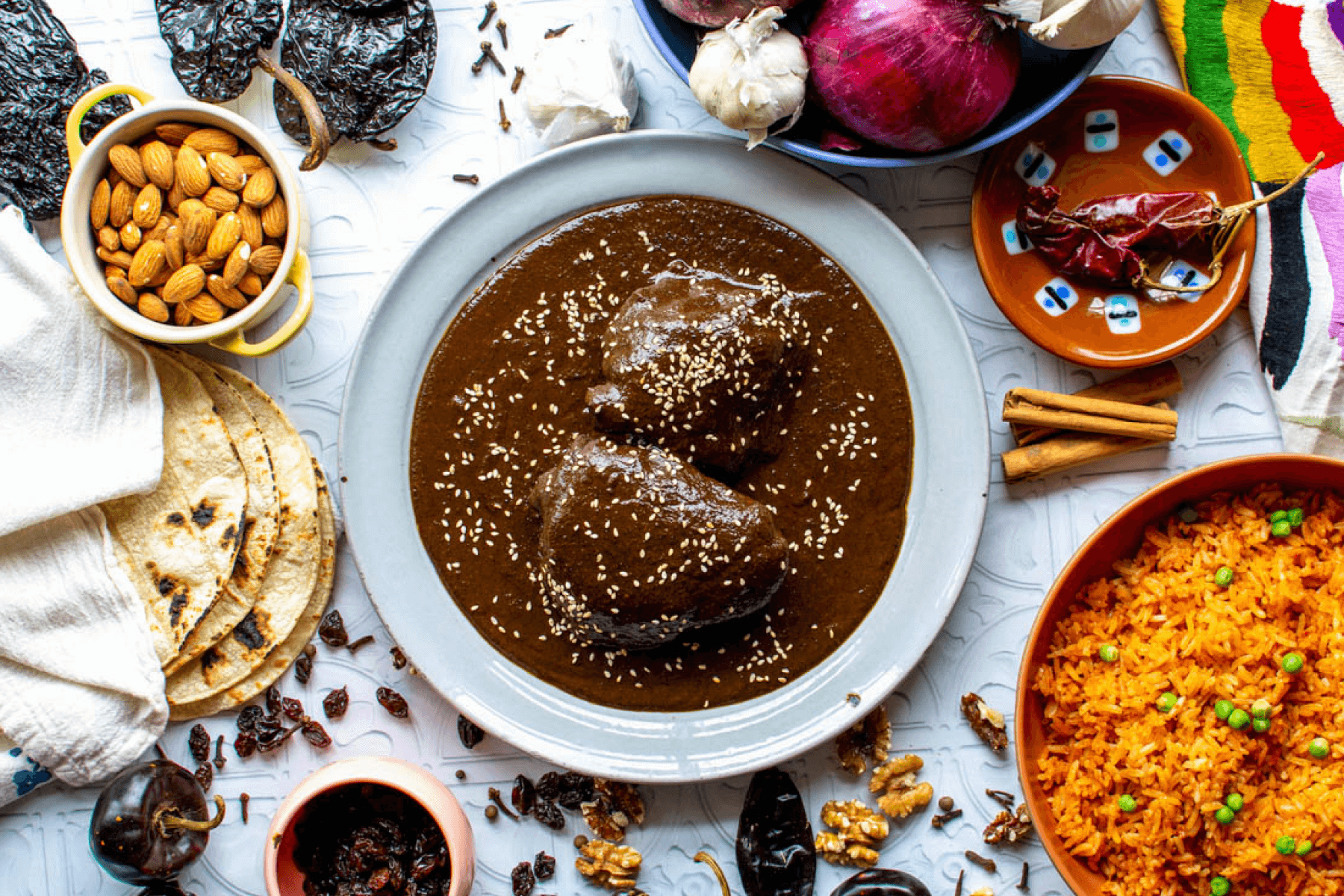 An overhead photograph of mole negro, rice, almonds, and tortillas.