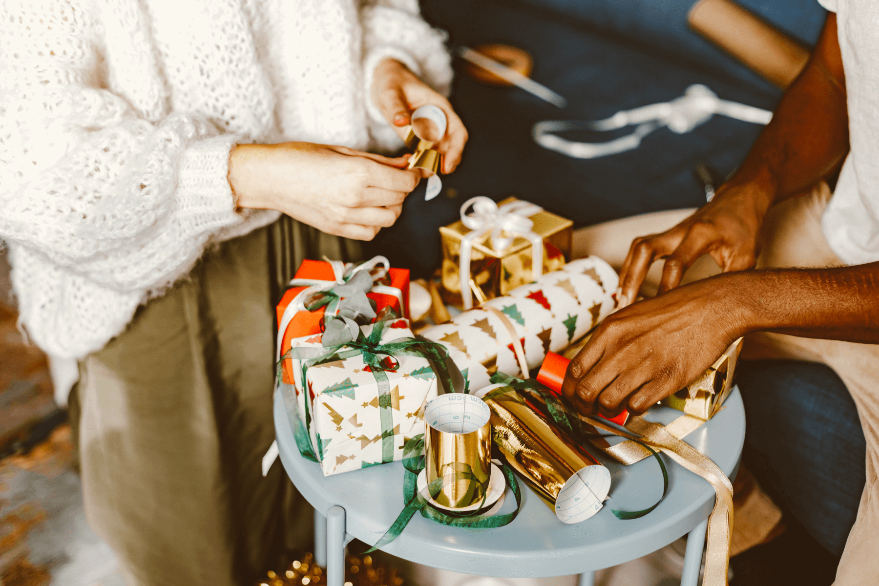 Close up photograph of two friends wrapping presents on a table.