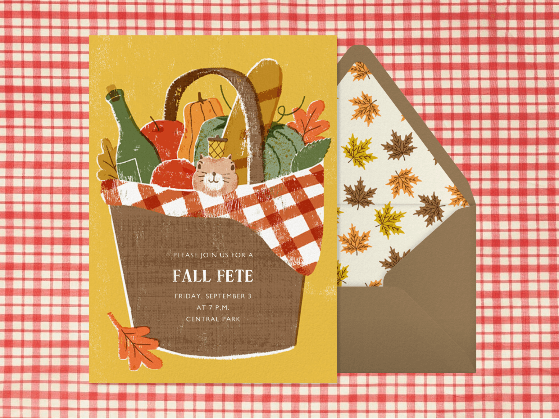 A fall invitation that features an illustration of a picnic basket full of wine, gourds, and bread. A squirrel with a nut on its head peeks out from behind the gingham liner.