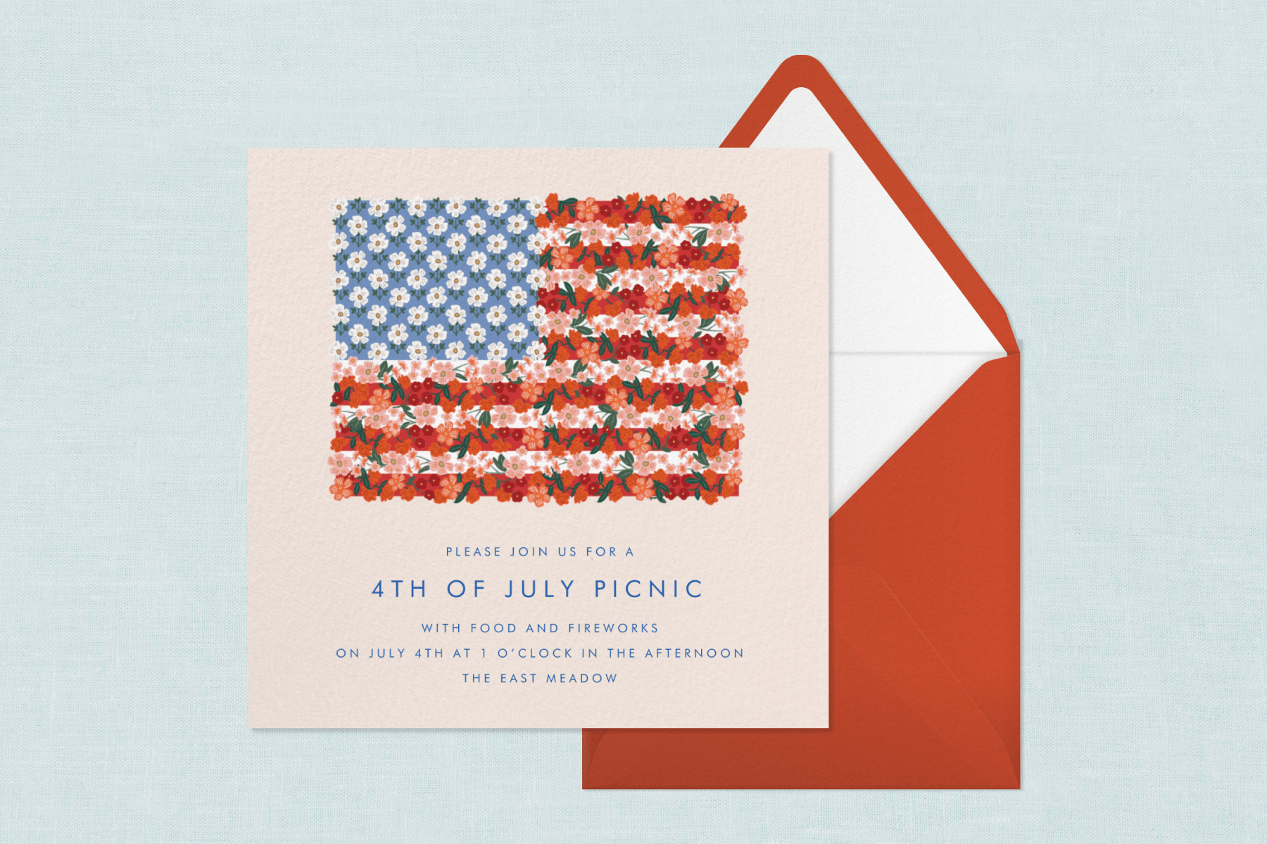 An American flag floral-themed 4th of July party invitation sits atop a red envelope with a white interior against a textured light blue backdrop.