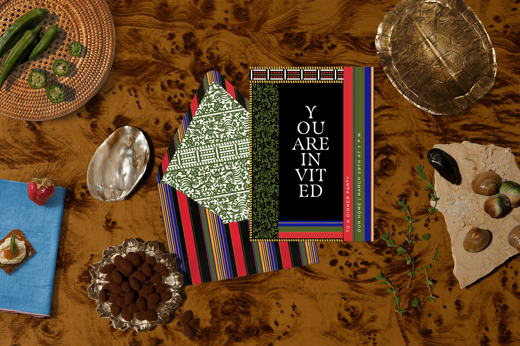 A Duro Olowu digital invitation with a layered, patterned frame around a black center that reads “You are invited.” The invitation is surrounded by objects like chocolate-covered almonds, shells, and okra.