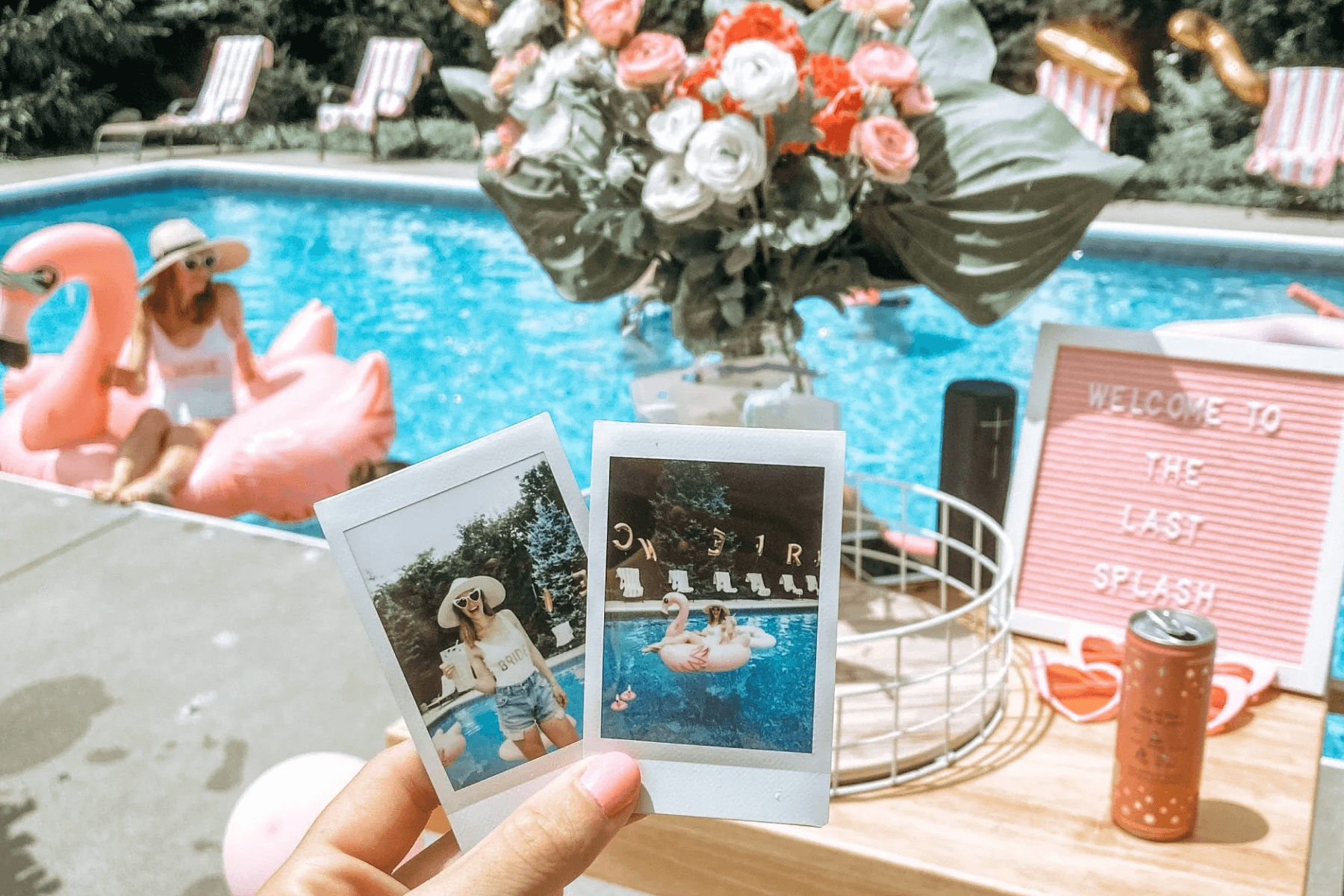 A hand holds up two Instax instant photos of women enjoying a pool day in front of an actual pool with flowers and someone on a pink flamingo float.