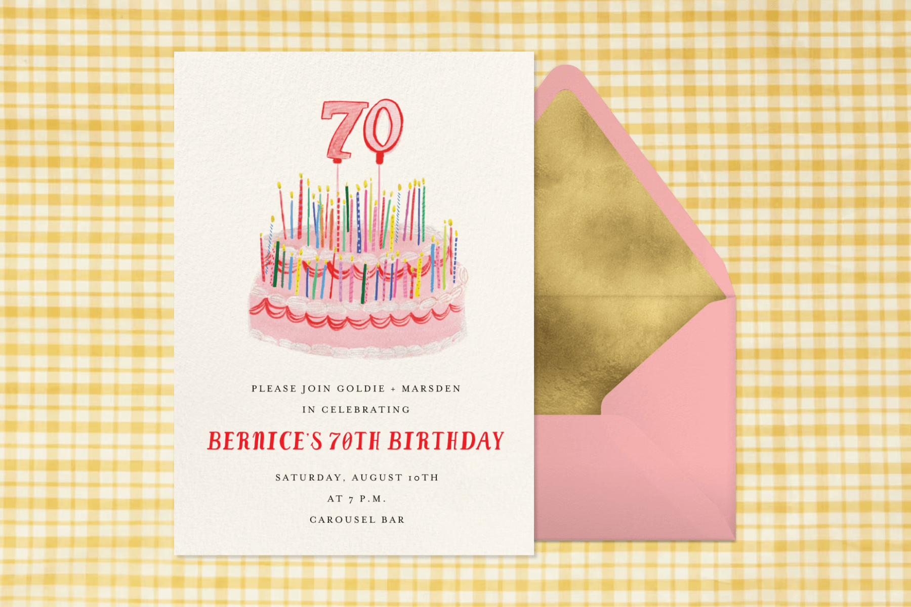 A 70th birthday party invitation with a pink cake illustration paired with a pink envelope, gold envelope liner, and yellow gingham background