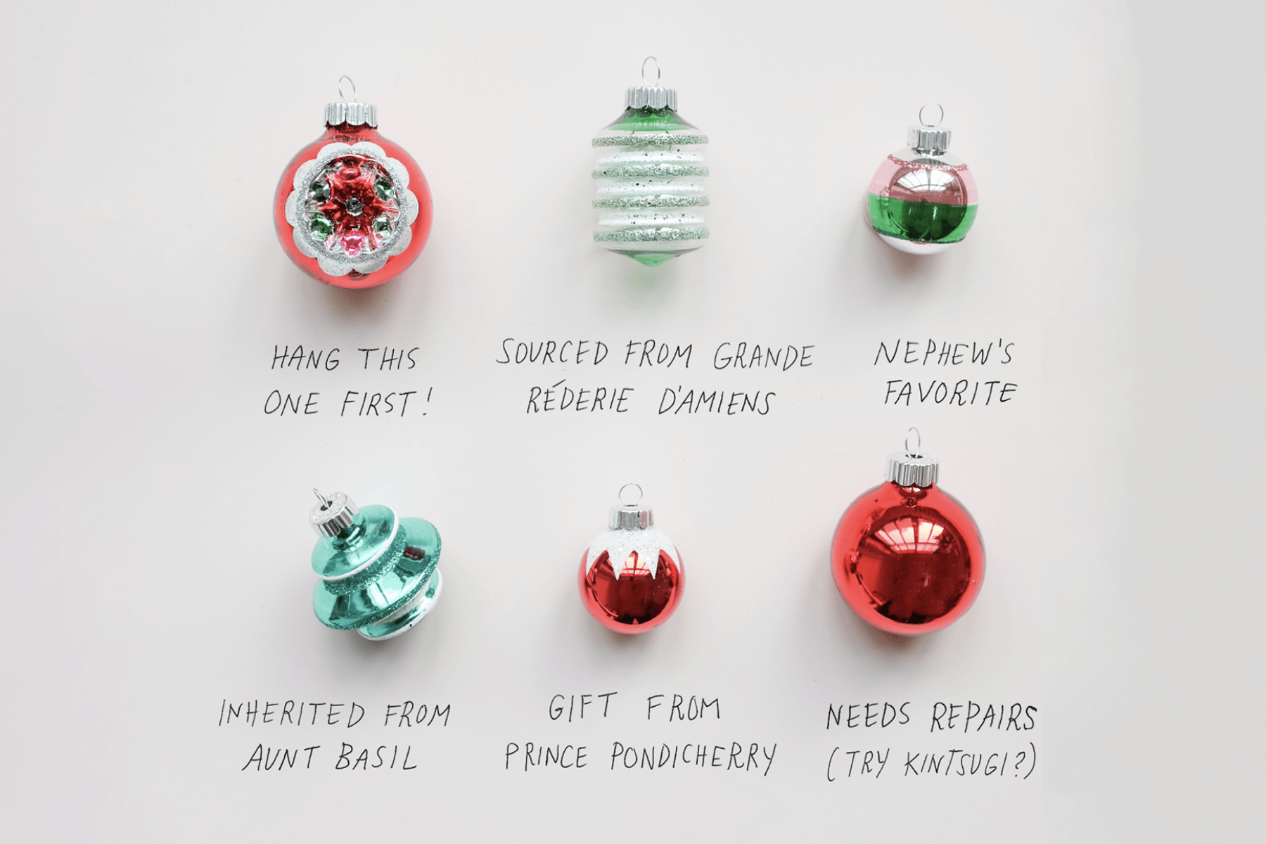 A flat lay photo of six red and green Christmas tree bulb ornaments with hand-written notes below each one about their origin and hanging instructions.