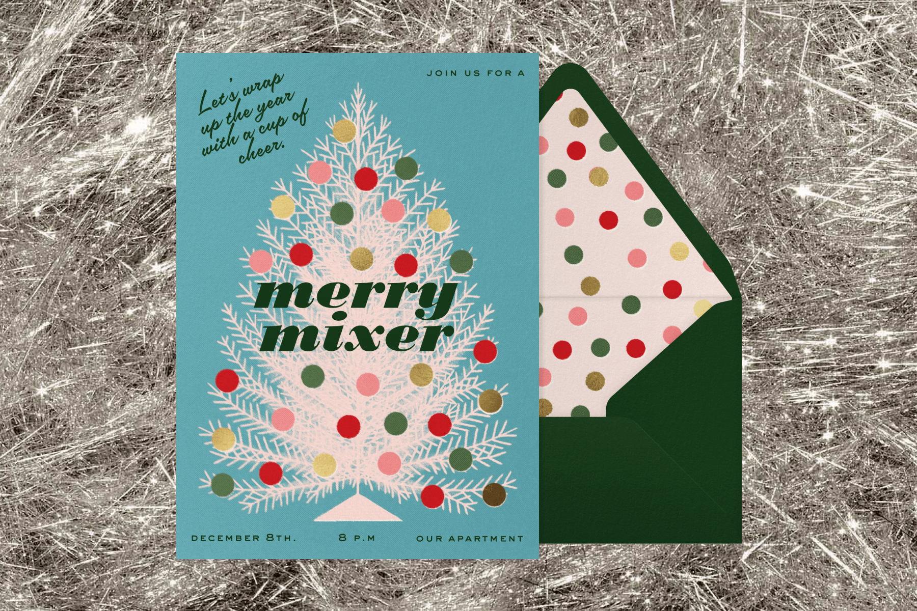 A silver tinsel background featuring a holiday invitation with a tree graphic and text that reads ‘merry mixer’ paired with a green envelope and polka dot envelope liner