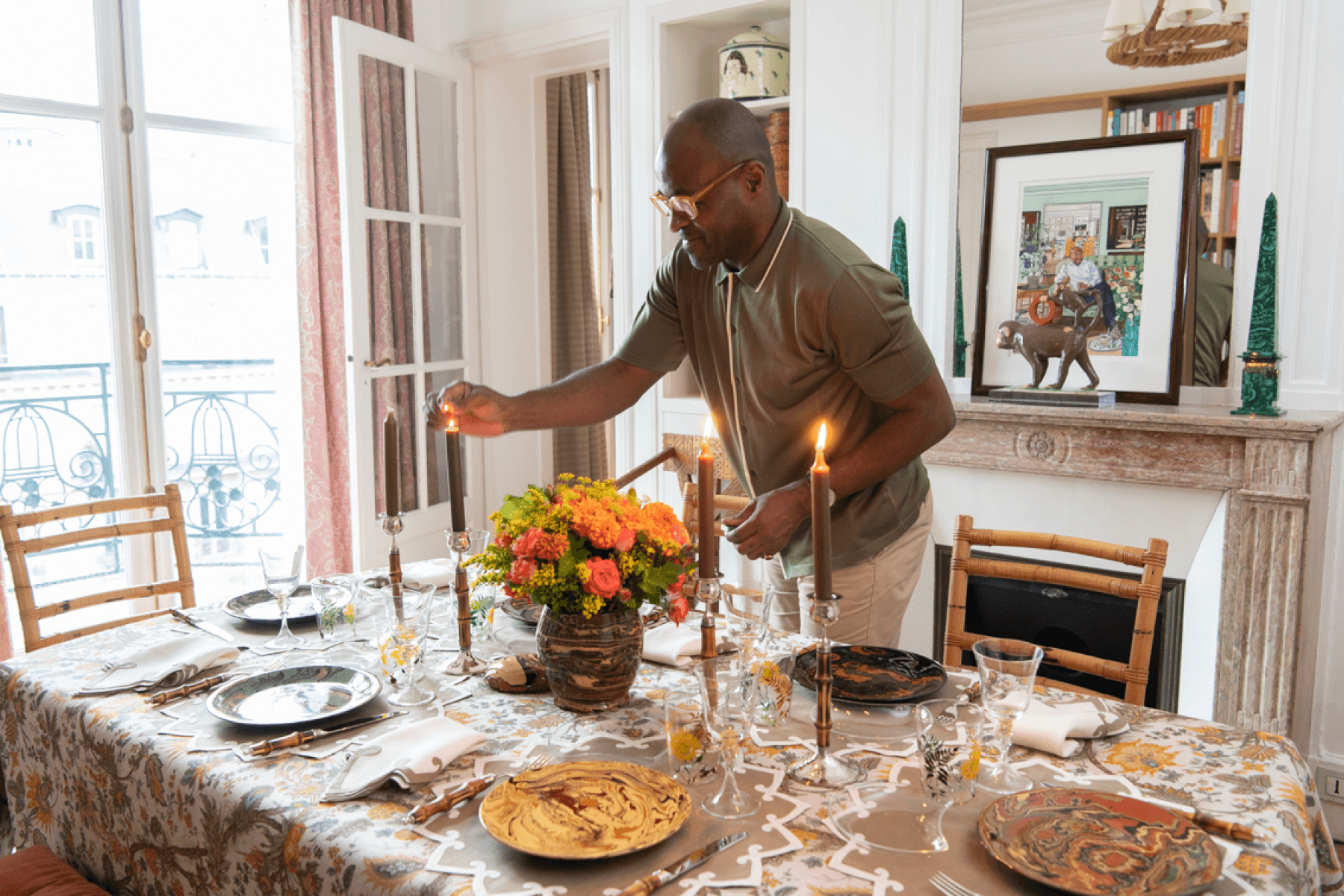 Man, Eric Goujou, lights the candles on a fall-themed dinner table set in his Paris apartment. 