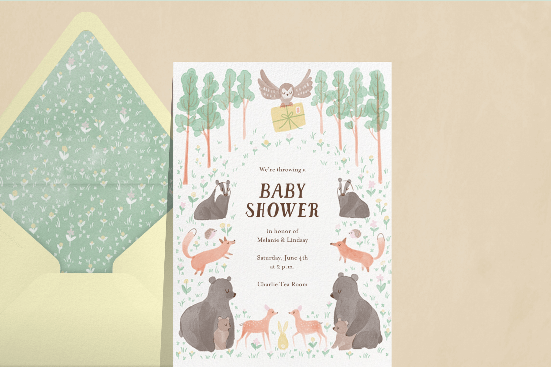 A baby shower invitation featuring woodland creatures and an owl with an invite.