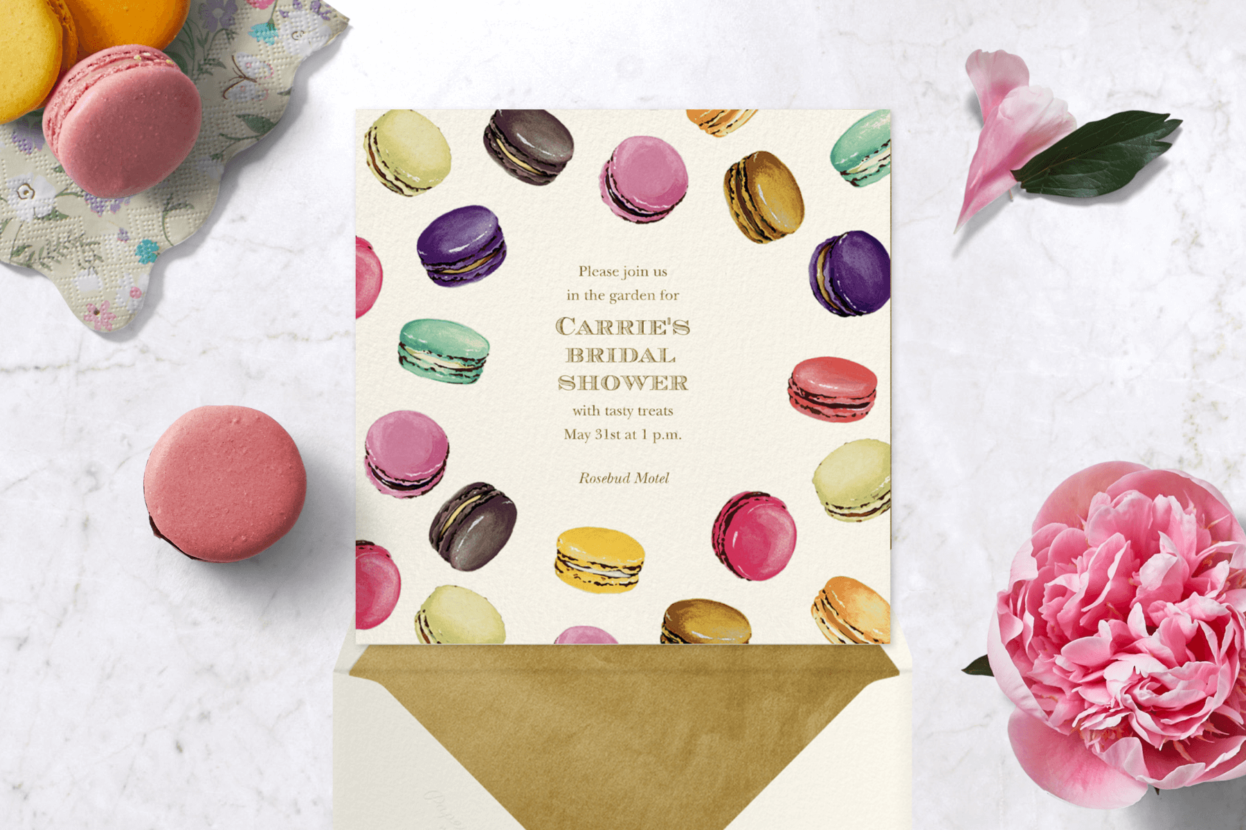 A square bridal shower invitation with colorful macarons floating all over.