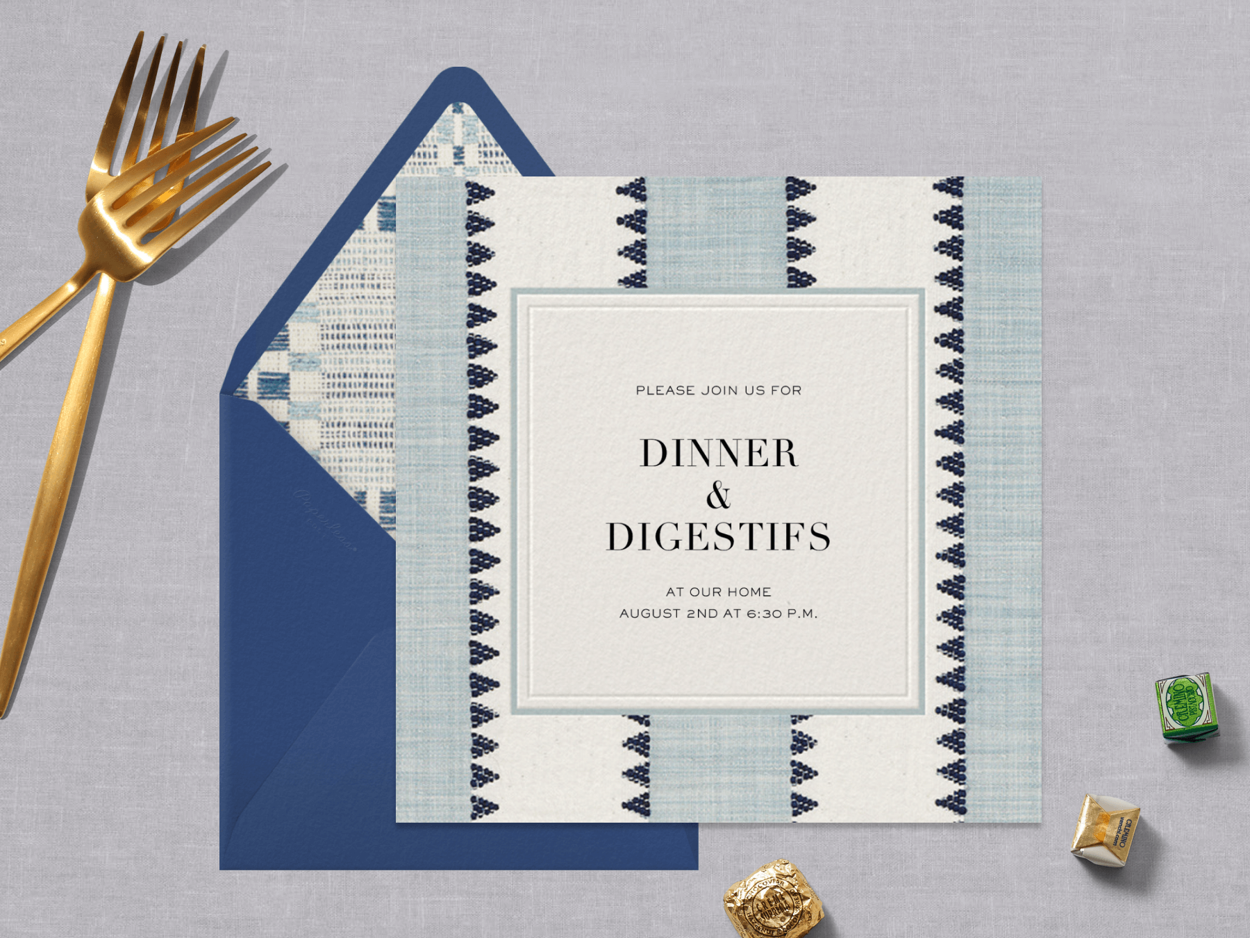 A dinner party invitation with textural light blue and white stripes with black teeth pattern next to gold forks.