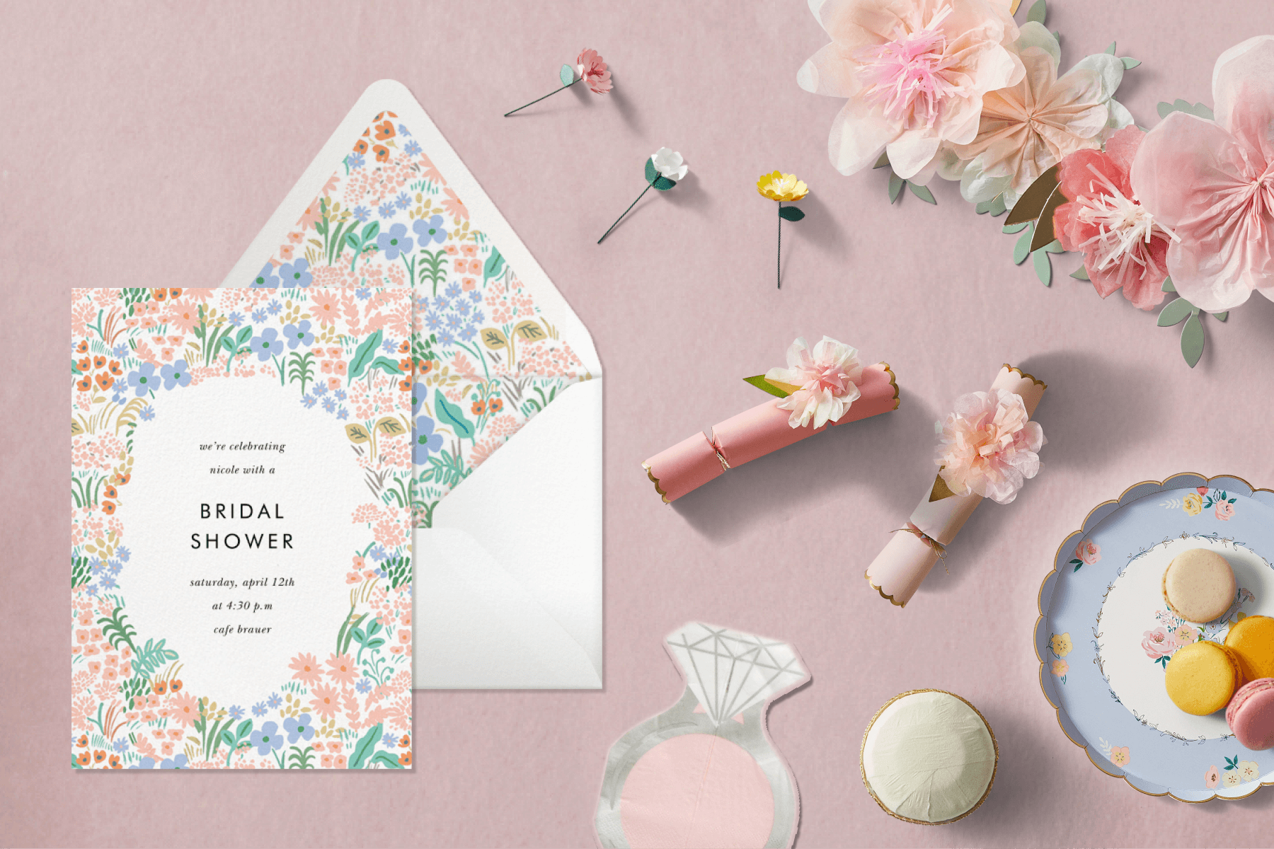 A bridal shower invitation and supplies like plates, poppers, and a garland.