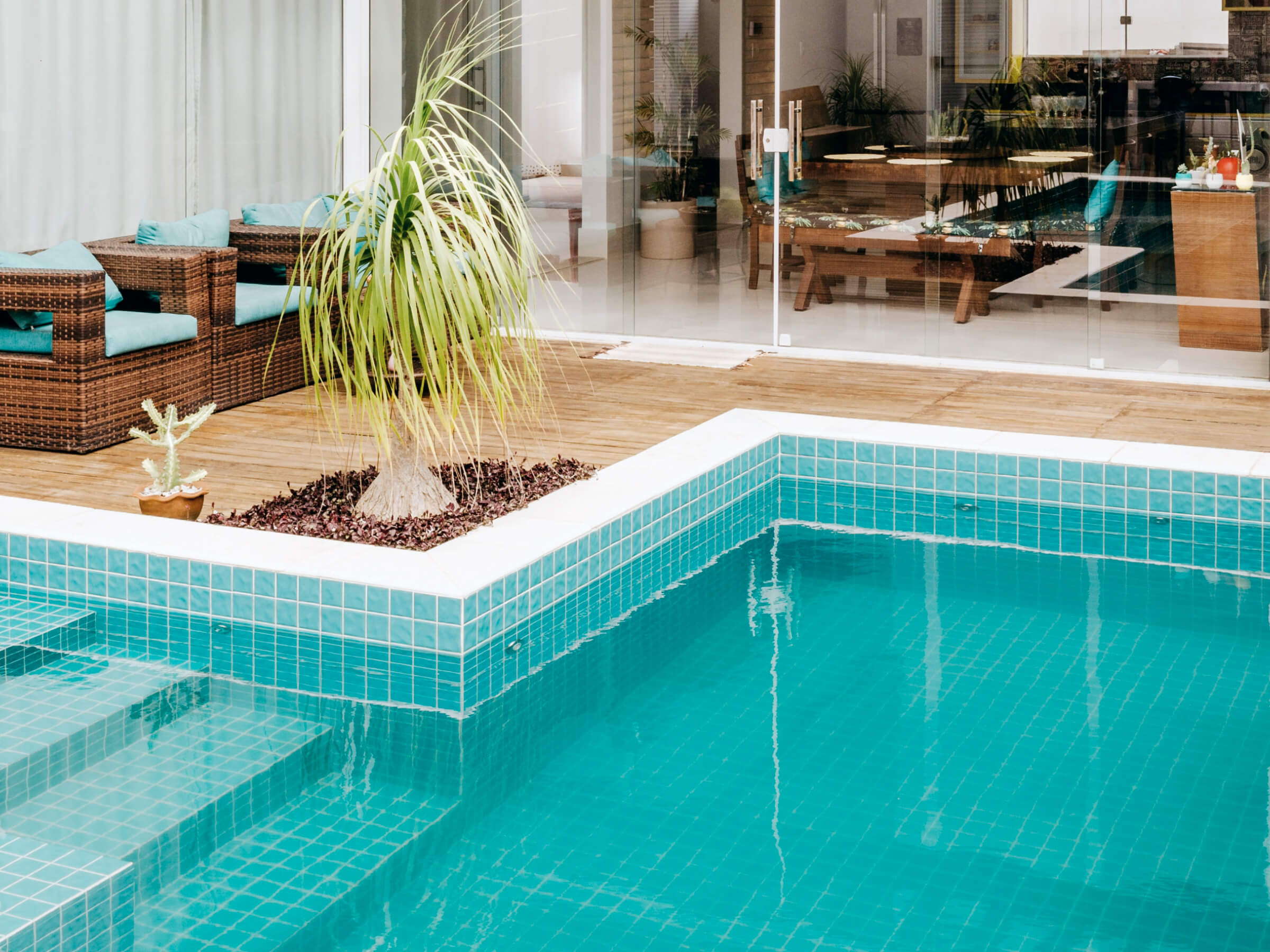 pool in the foreground and a glass-enclosed living room in the background