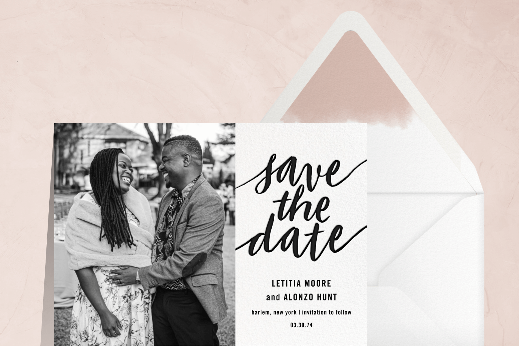 A save the date card with a black and white photo of a man and woman embracing on the left and “save the date” in black script beside an envelope with a pink dip-dyed liner.