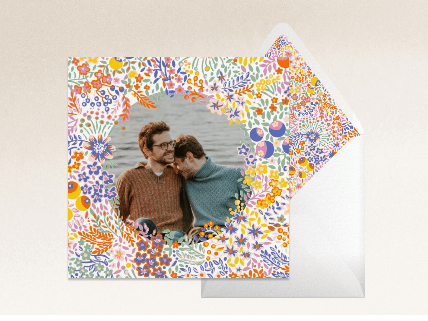 A square card with colorful floral doodles around a photo of two men and a matching envelope.