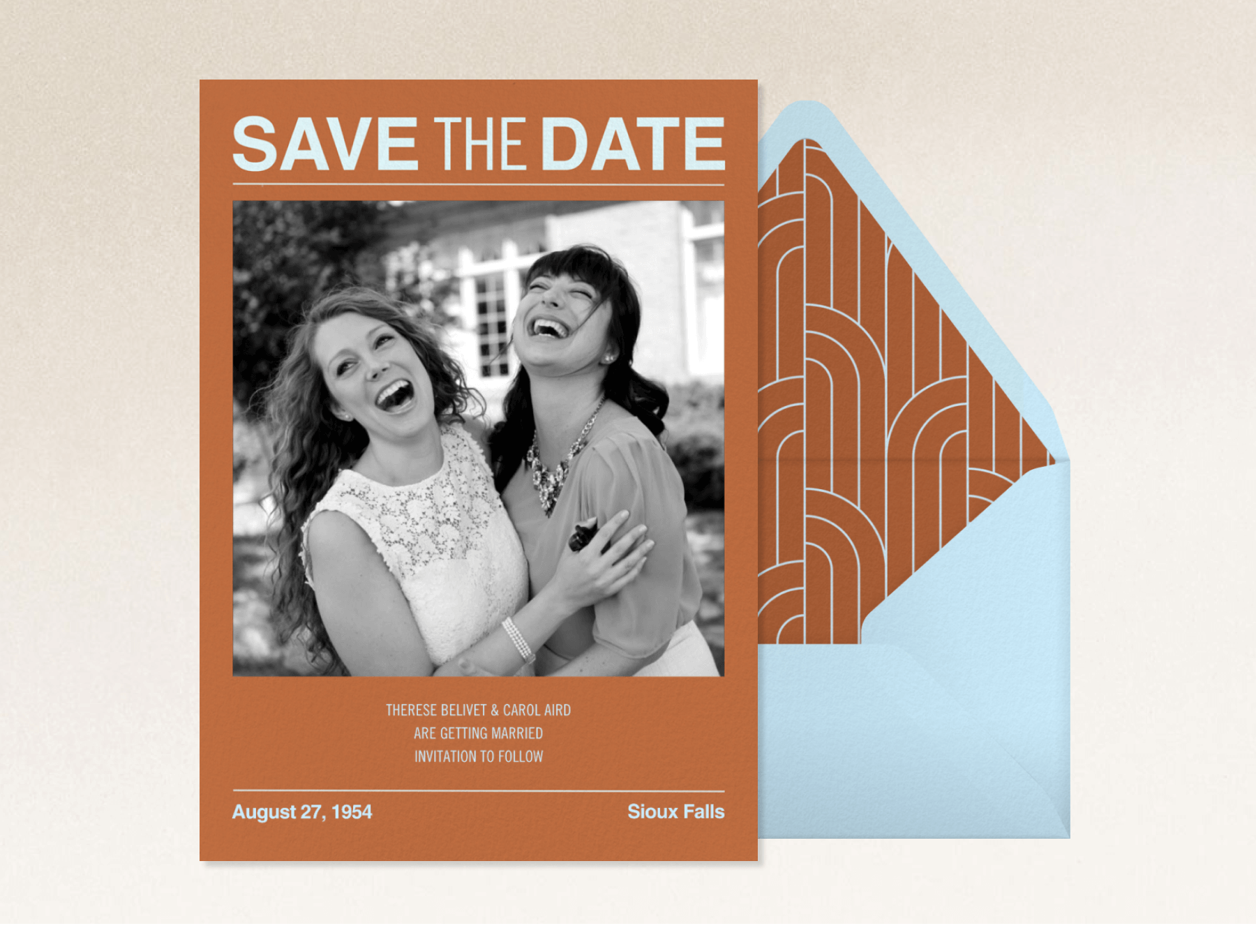 A brownish-orange save the date with a photo of two women happily embracing and a light blue envelope with a matching liner.