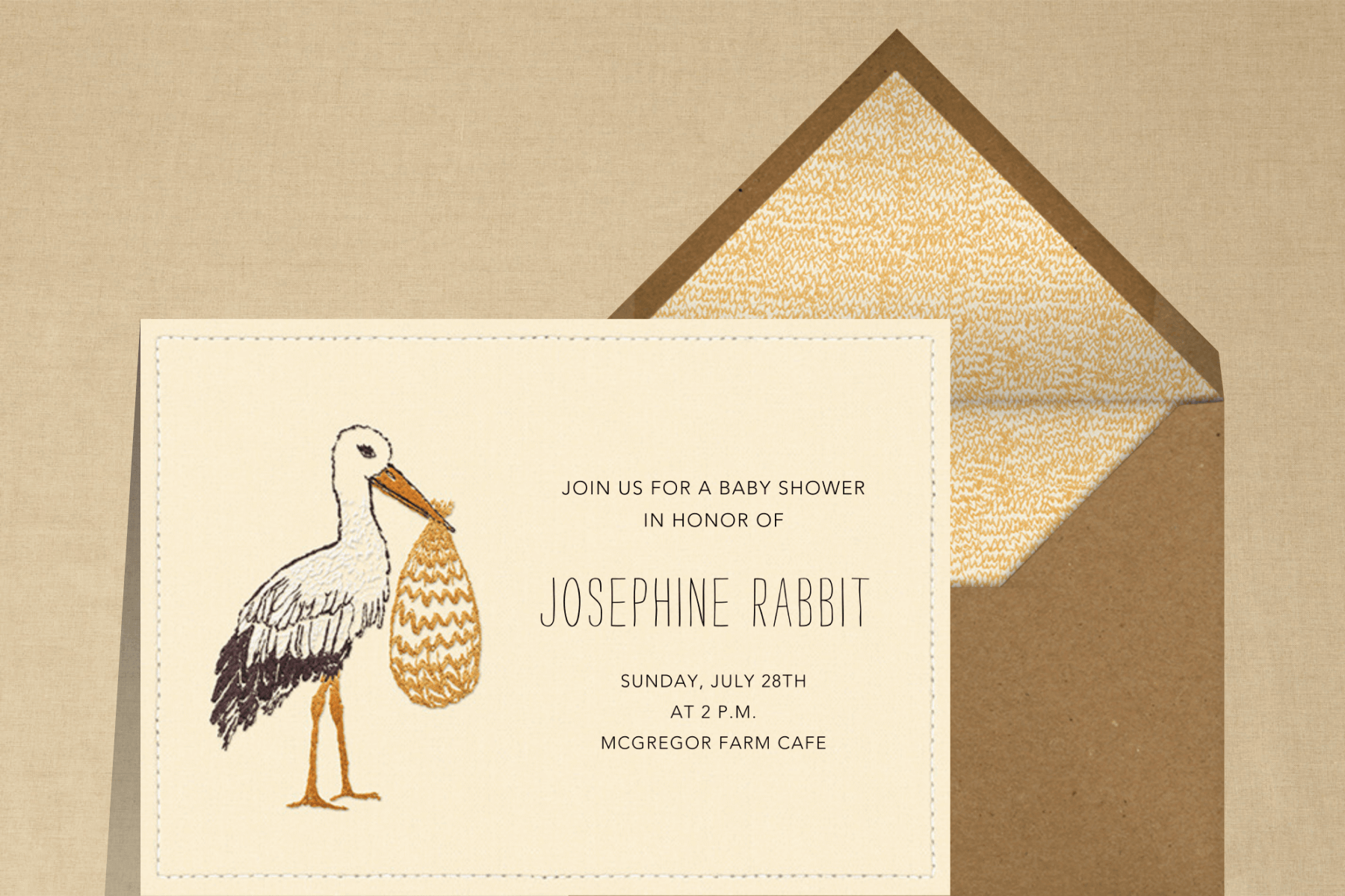 An invitation featuring an embroidered stork carrying a bundle.