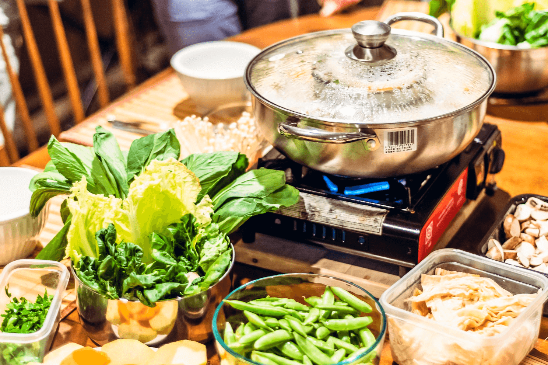 A hot pot spread with lots of vegetables in individual containers.