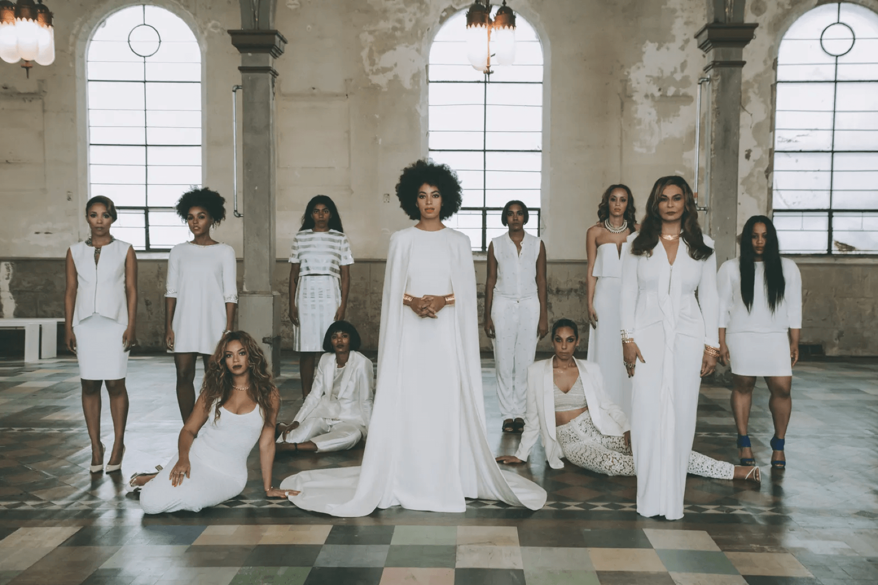Solange Knowles stands in a bare room with her wedding party. They are all wearing white.