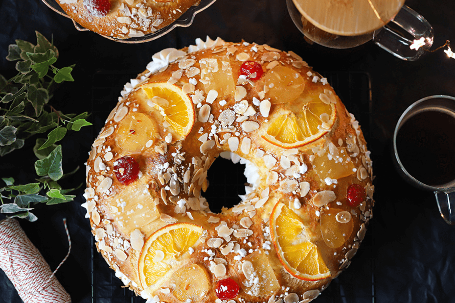 A roscón de Reyes decorated with oranges, cherries, and sliced nuts. 