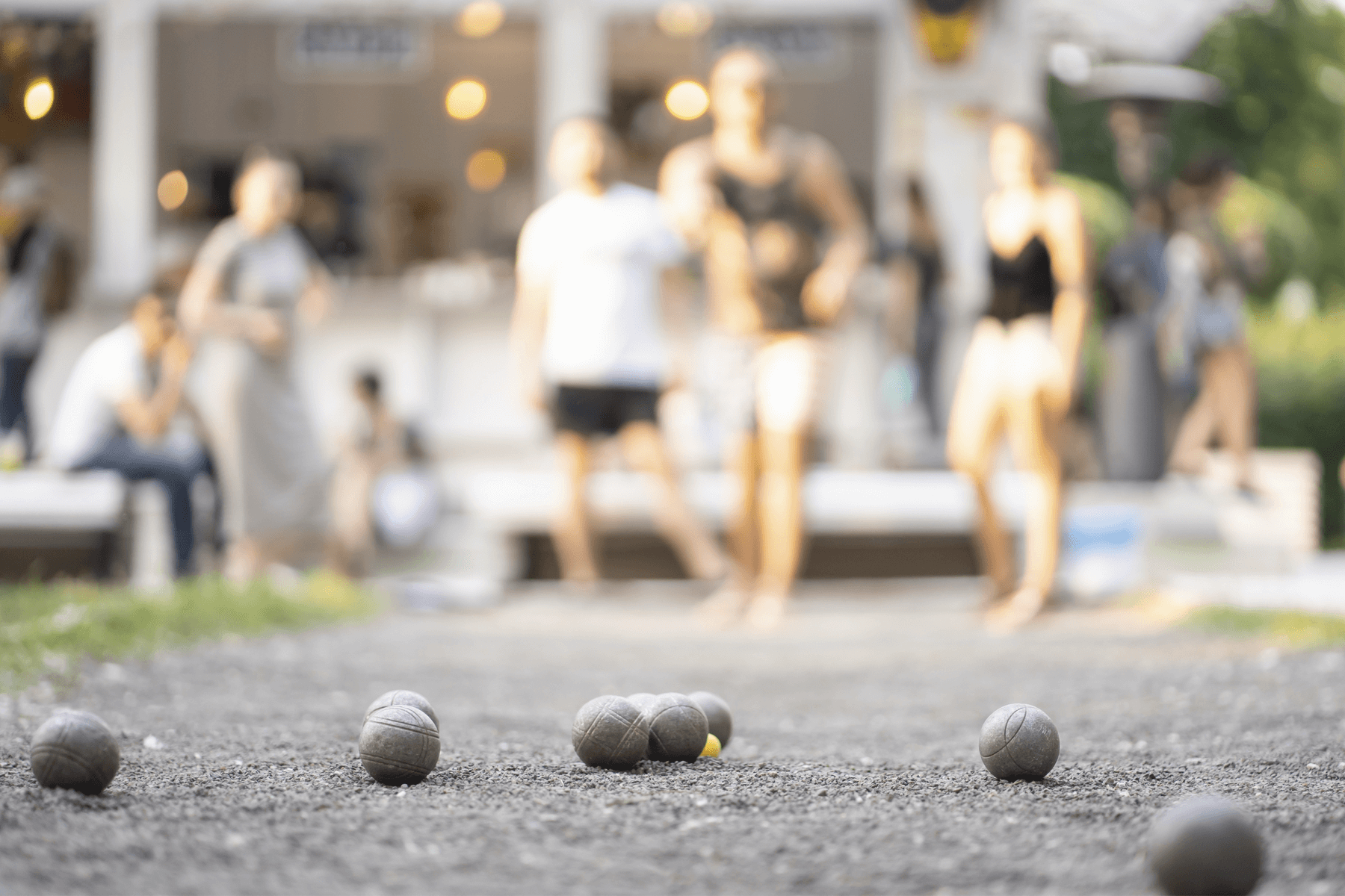 An out-of-focus group of people plays a game of bocce. 