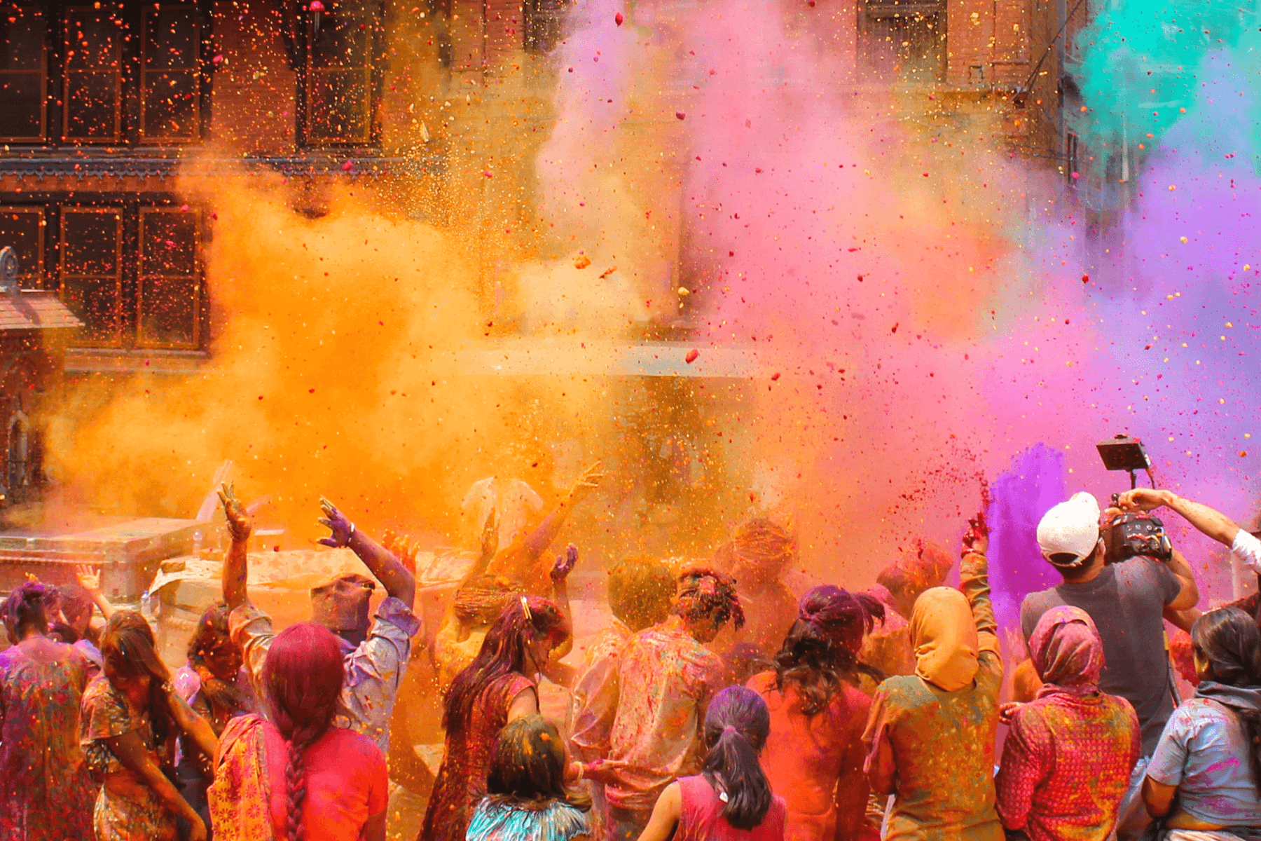 A group of revelers throw colors in the air at a Holi celebration.