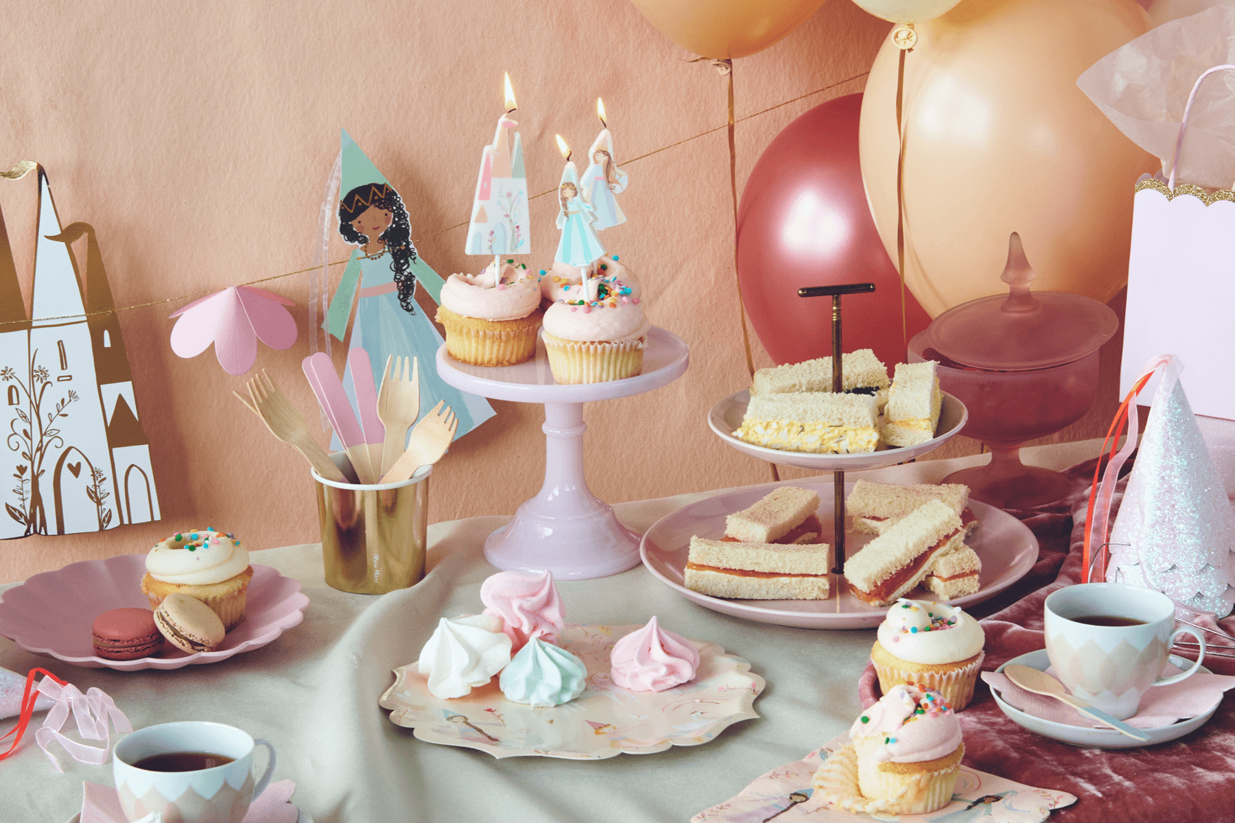 A table decorated for a princess themed birthday party, including cupcakes and tea cups.