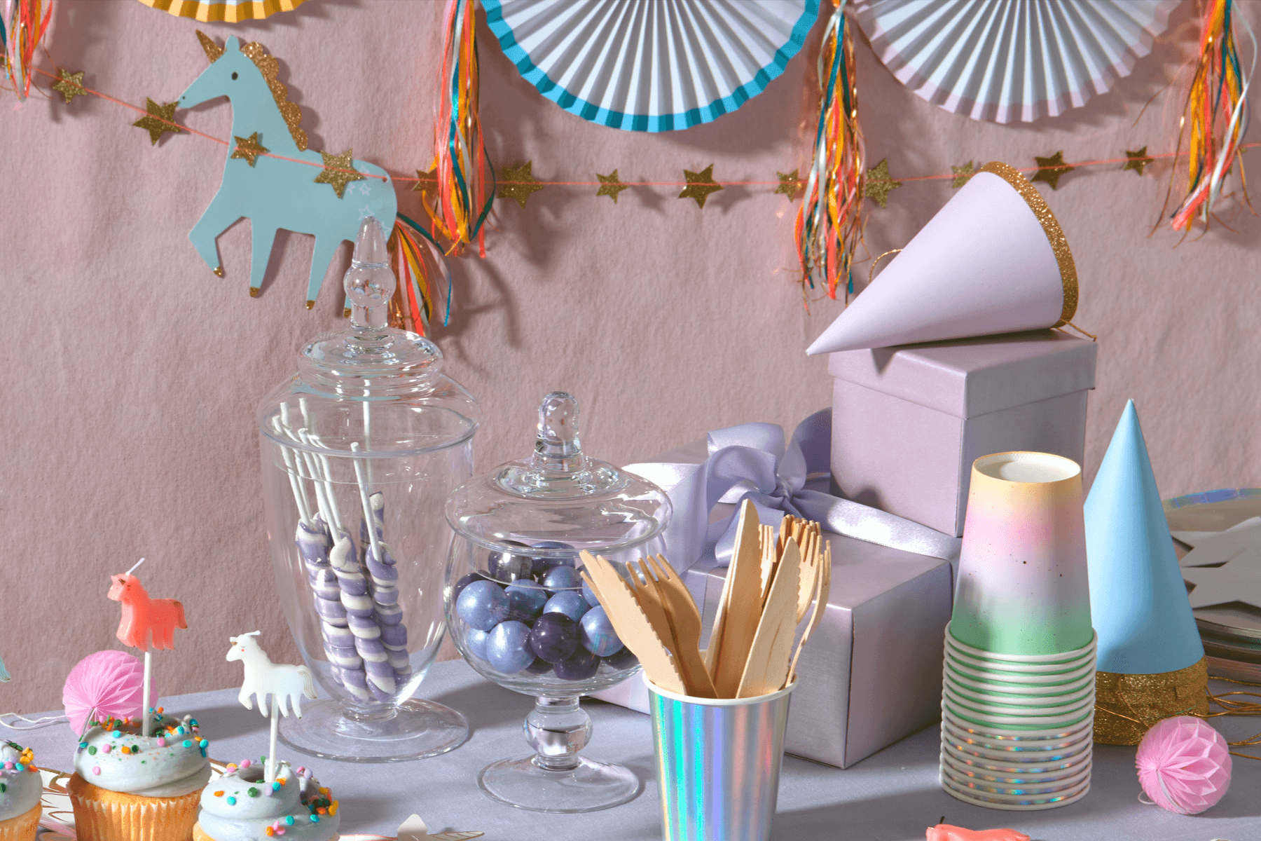 Unicorn and pastel party supplies on a table.