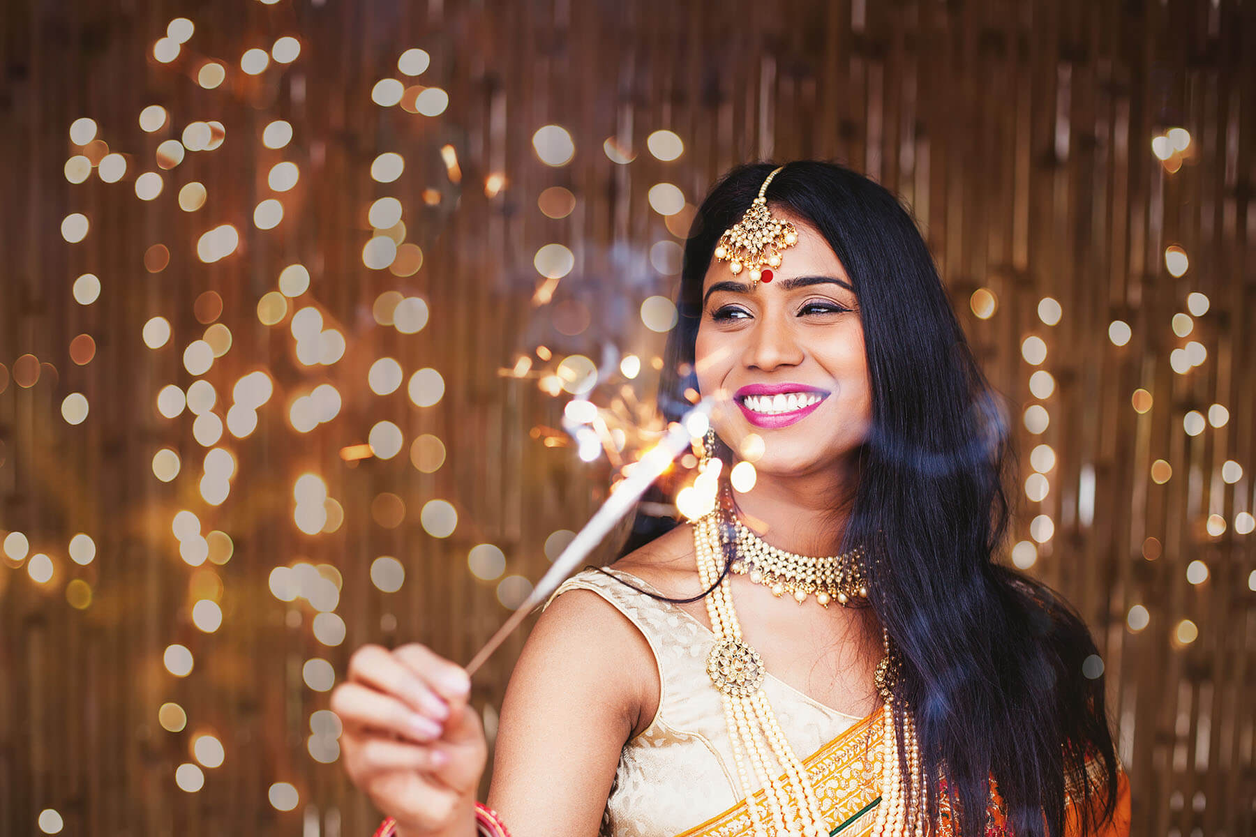 A woman in a sari holds a sparkler.