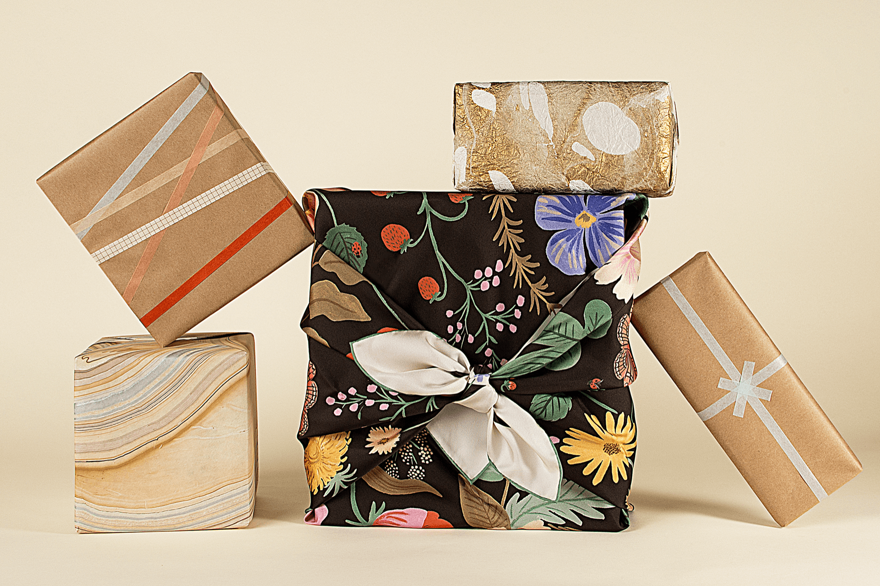 Stack of eco-friendly wrapped gifts on a beige background.