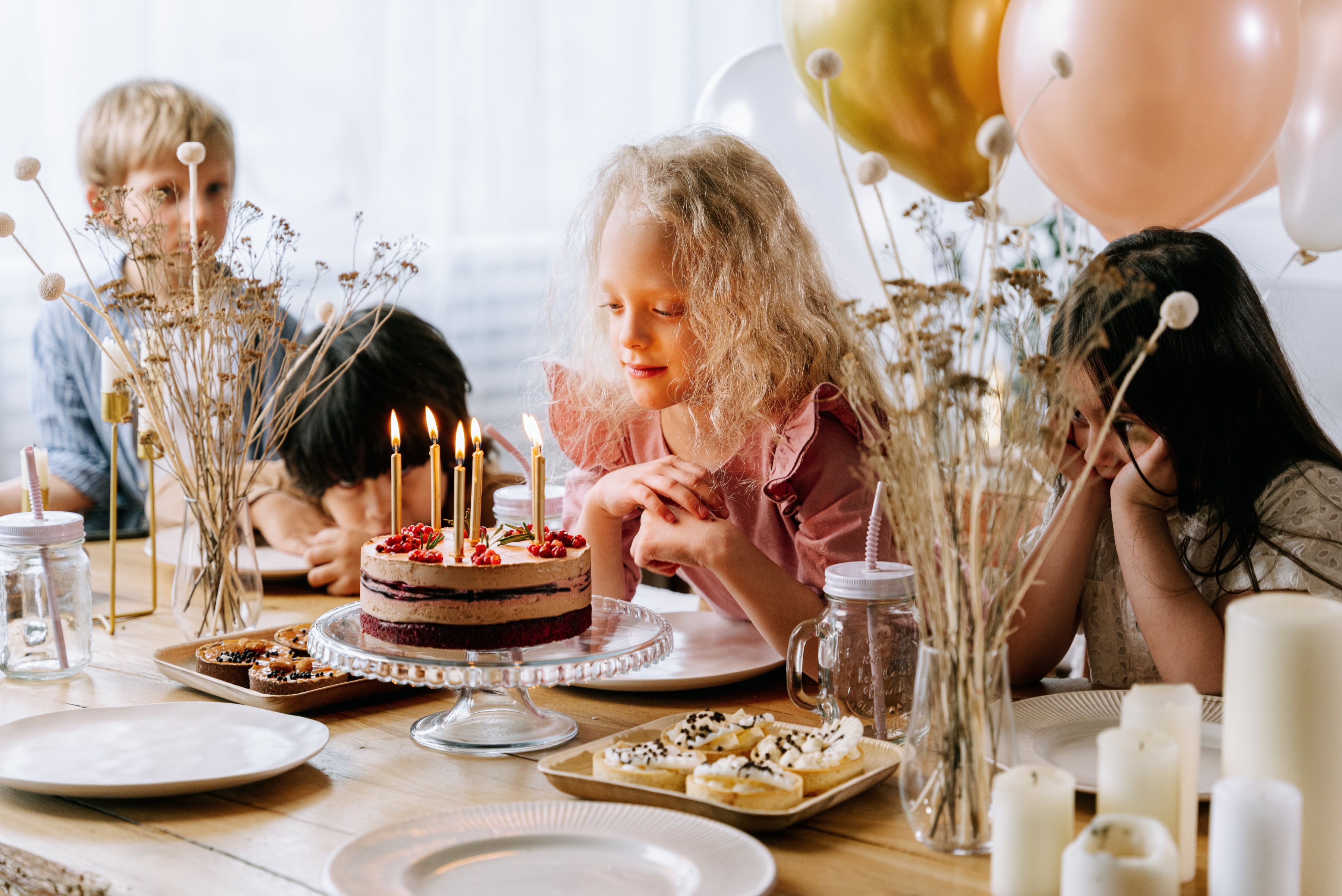 A little girl making a wish on birthday candles at a party.