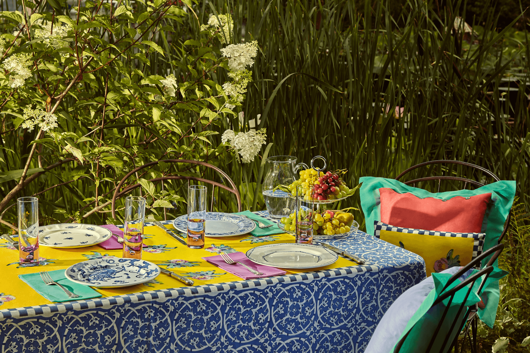 Outdoor table set with a vibrant yellow and blue tablecloth from textile designer Lisa Corti.