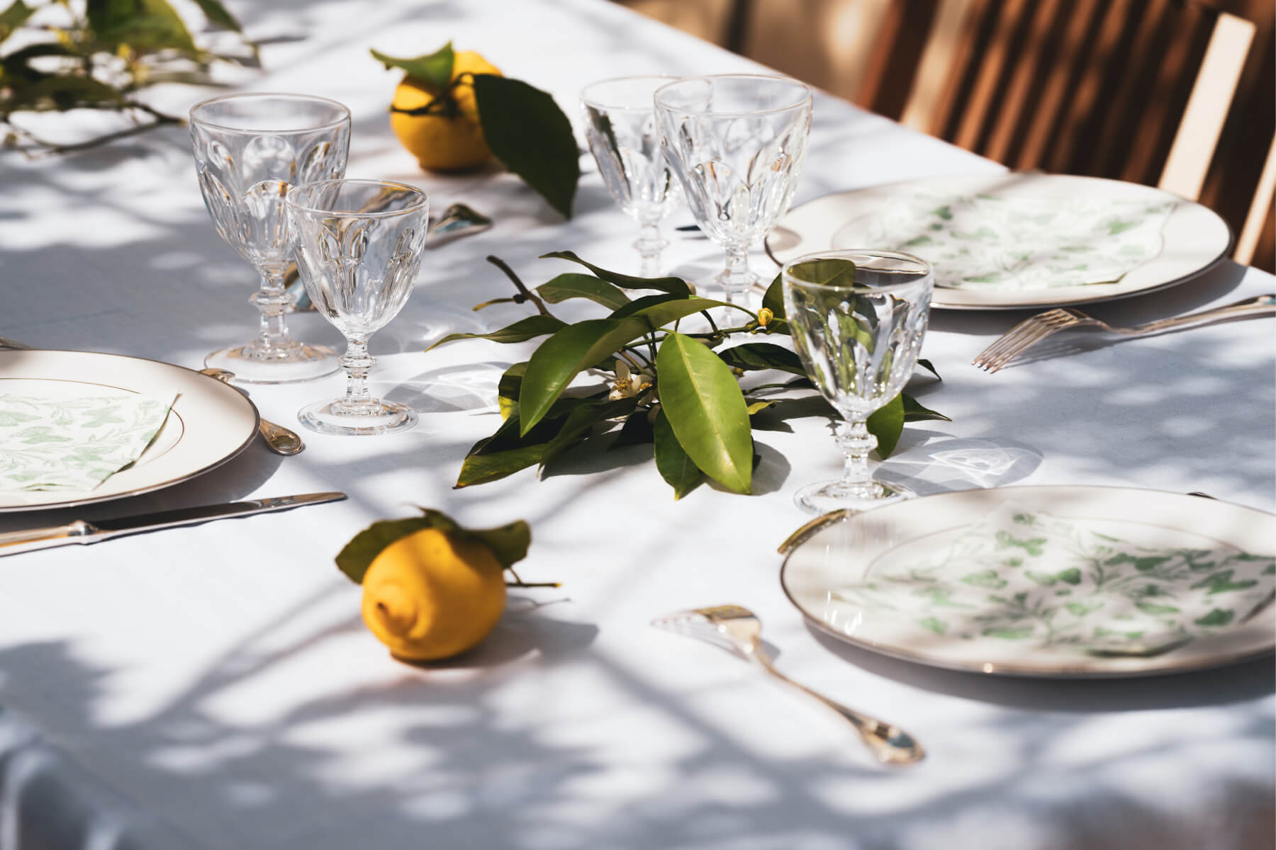 Table settings with lemons, crystal stemware, and white plates.