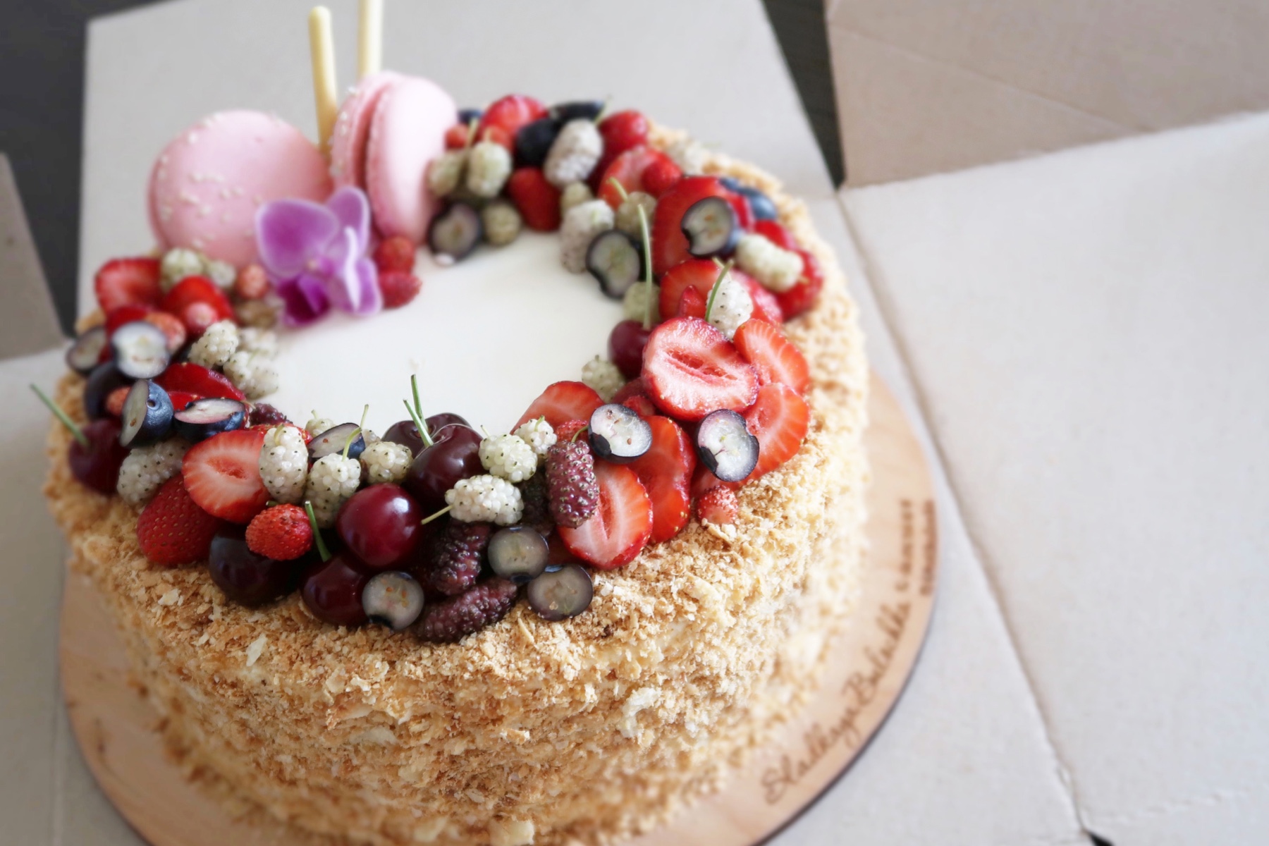 Photo of a cake covered in strawberries, macarons, and other treats